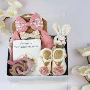 Baby girl gift box with pink bow, crocheted bunny, baby shoes, and The Tale of the Flopsy Bunnies book