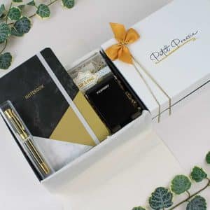 A beautifully arranged professional gift box containing a marble and gold-accented notebook, gold pen, phone stand, and stylish clips and pins, ideal for gifting.