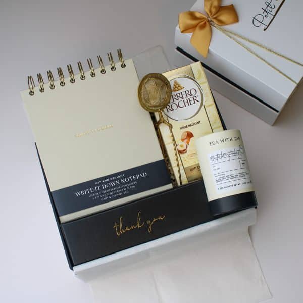 Golden Moments Gift Box open with gold ribbon, chocolates, tea, and notepad inside