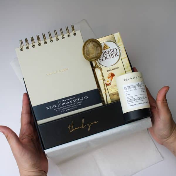 Elegant flat lay of luxury thank you gift box with white orchids and premium contents