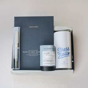 Flat lay of Christian self-care gift box with calming tea, stress candle, luxury journal, and pen – Petit Pressie box for women