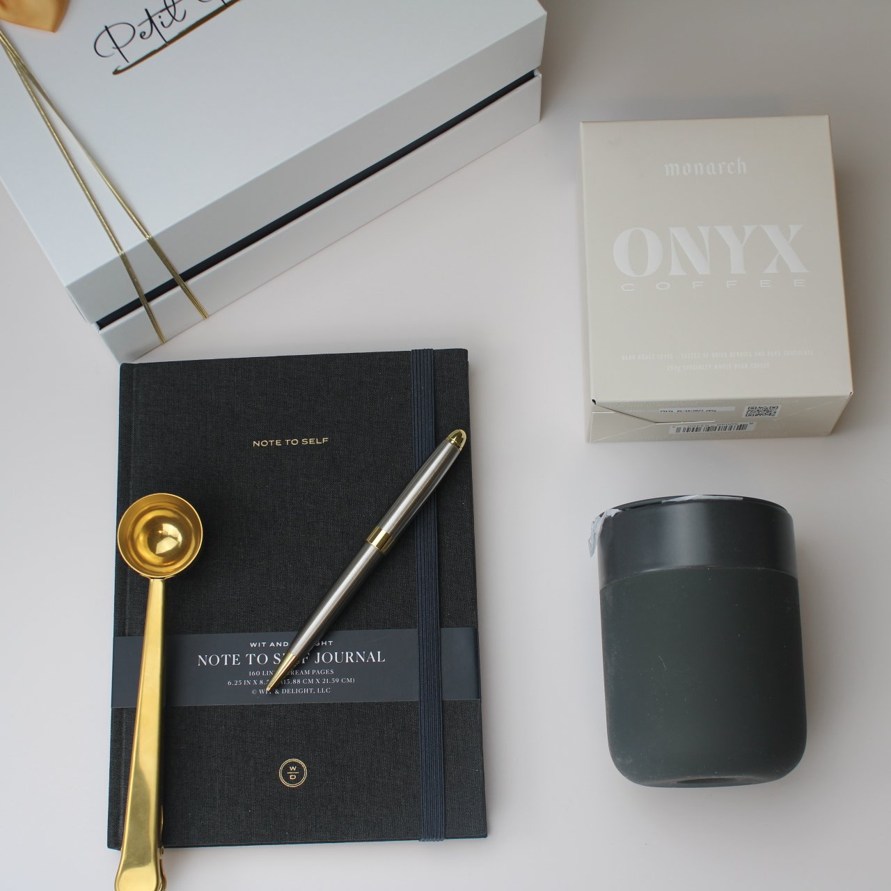 “Start with Intention” Gift Box – Coffee, Clarity & Purpose 4 Flat lay of Christian gift box components — journal, Onyx coffee, ceramic mug, pen, and gold scoop, with Petit Pressie box in background